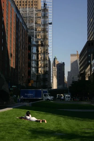 08.04.2007 Nova Iorque, EUA. Uma mulher está descansando na grama entre os arranha-céus. — Fotografia de Stock