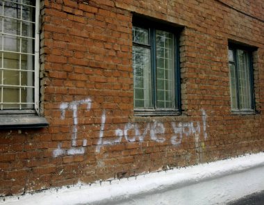 Tuğla duvardaki yazı seni seviyorum. Pencerelerde parmaklıklar var. Sosyal dezavantaj. Getto.