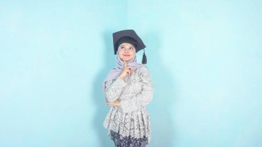 Mezuniyet şapkasıyla düşünen mutlu Asyalı öğrenci.