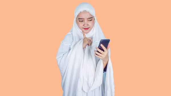 ラマダーン アイド フィトル アイド ムバラクのコンセプト イスラム教徒のヒジャーブスカーフを身に着けている深刻なアジアの女性ムケナ電話を保持することは インターネット読書メディア — ストック写真