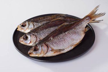 Yuvarlak tabakta kurutulmuş hamamböceği balığı, beyaz arka planda izole edilmiş bira atıştırmalığı.