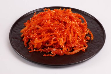 Yuvarlak tabakta kırmızı biber ile susam tohumlu mürekkep balığı parçaları, beyaz arka planda izole edilmiş bira için aperatif