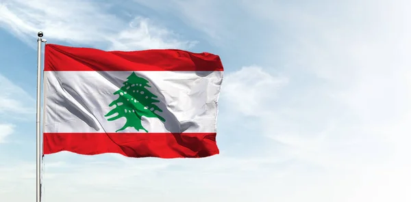 Lebanon flag in the blue sky. Horizontal panoramic banner.