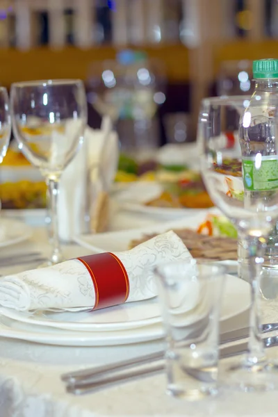 Una mesa en el restaurante, el mantel blanco y platos, tenedores y cuchillos, vasos, servilletas , — Foto de Stock