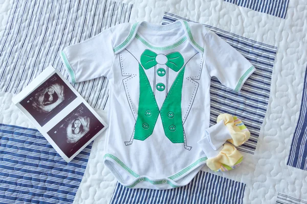 Kleidung für Babys und Ultraschallbild auf das Laken gelegt — Stockfoto