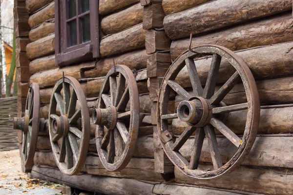 Antika wagon wheel lutad mot gamla trävägg — Stockfoto