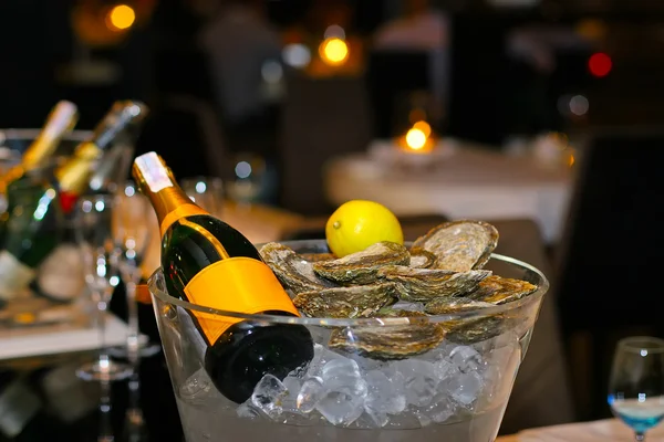 Bouteille de champagne au citron et huîtres fraîches dans un seau avec glace — Photo