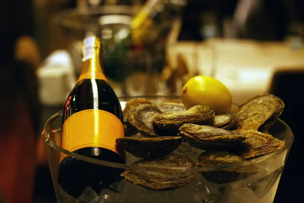 Champagne bottle with lemon and fresh oysters in a bucket with ice — Stock Photo, Image