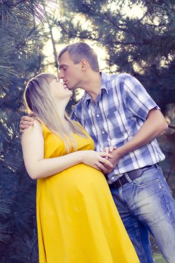 Mutlu ve genç hamile çift doğa üzerinde