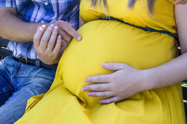 Счастливая и молодая беременная пара на природе — стоковое фото