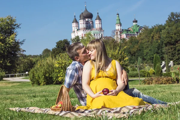 Pasangan muda hamil santai pada piknik di taman — Stok Foto