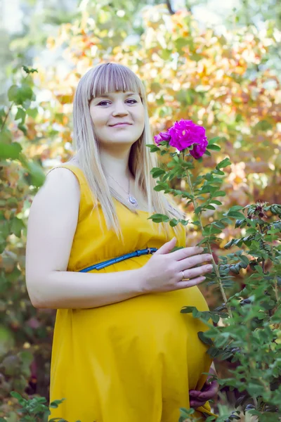 Jeune fille enceinte près de fleurs — Photo