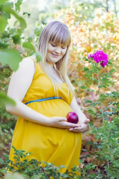 Молодая беременная девушка рядом с цветами — стоковое фото