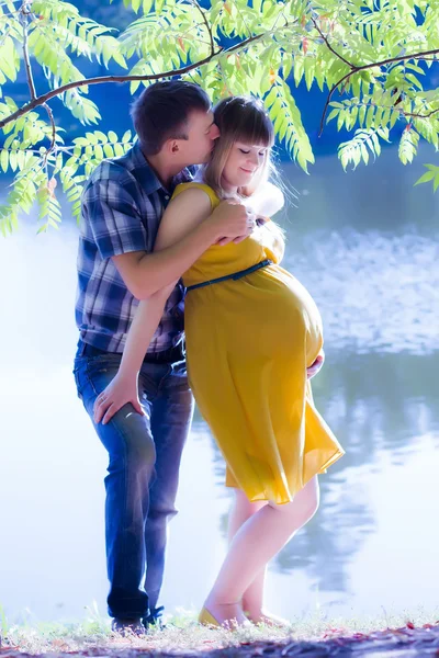 Feliz y joven pareja embarazada en la naturaleza — Foto de Stock