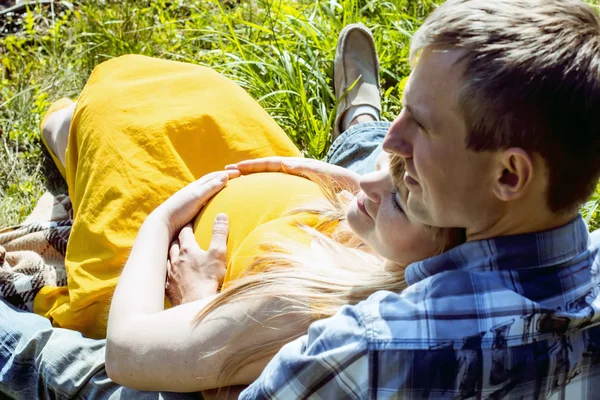 Giovane coppia incinta rilassarsi su un picnic nel parco — Foto Stock