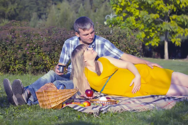 Молодая беременная пара отдыхает на пикнике в парке — стоковое фото