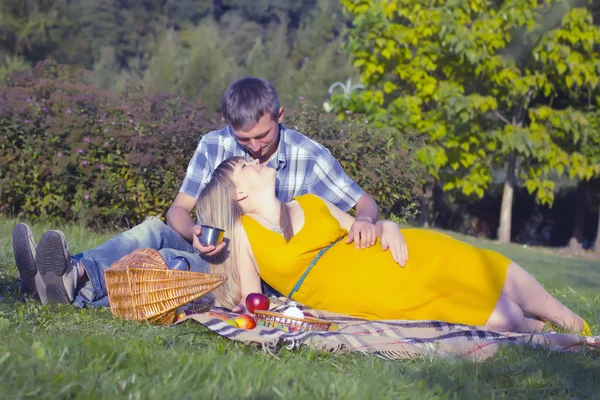 Молодая беременная пара отдыхает на пикнике в парке — стоковое фото