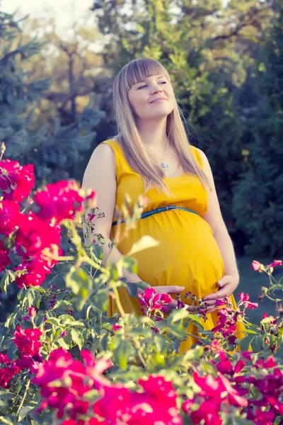 Jeune fille enceinte près de fleurs — Photo