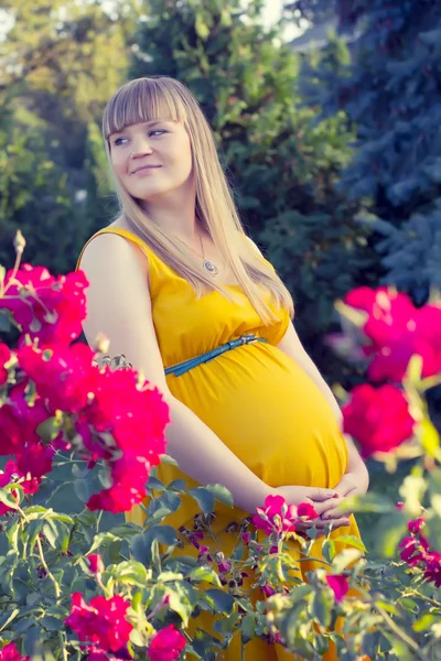 Jeune fille enceinte près de fleurs — Photo