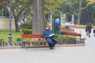 Şehir Parkı yaşlı bir adam bir gazete okuyan bir bankta oturur