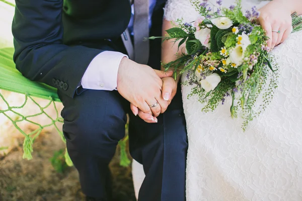 Brud- och brudgummen håller varandra i handen — Stockfoto