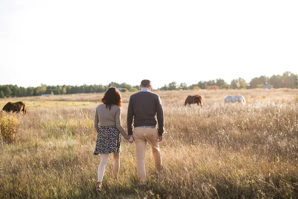 Young couple walks at sunset holding hands