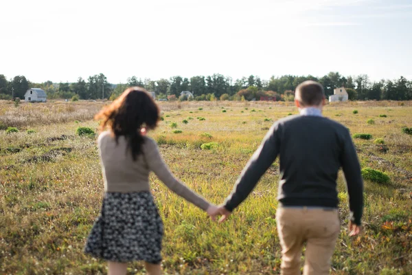 Junges Paar geht bei Sonnenuntergang Händchen haltend spazieren — Stockfoto