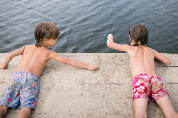 Fraternal twins tanning on wooden deck at the lake on hot summer day — Stock Photo, Image