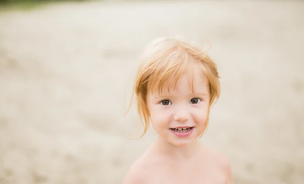 Ragazza bambino con i capelli rossi in spiaggia sorridente alla macchina fotografica — Foto Stock