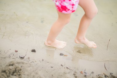 Plajda su ayaklarda yürümeye başlayan çocuk