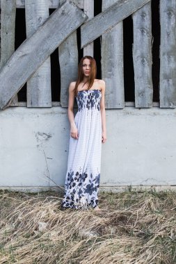 Terk edilmiş binada yakınındaki çiçek elbiseli kızıl saçlı genç bayan