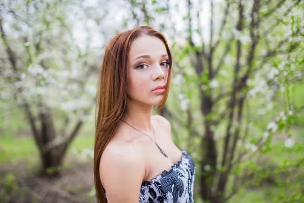 Red-haired lady in spring orchard — Stock Photo, Image