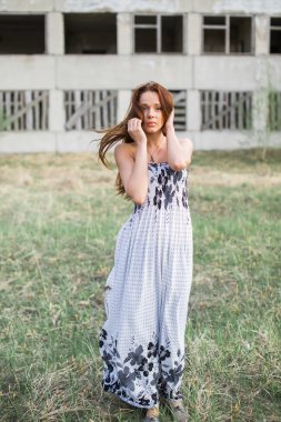 Terk edilmiş binada yakınındaki çiçek elbiseli kızıl saçlı genç bayan