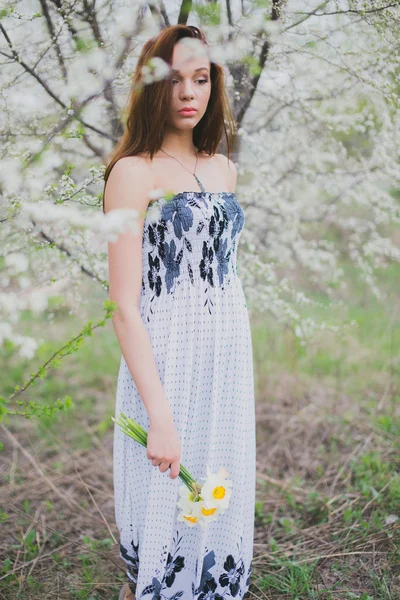 Рудоволоса молода леді з нарцисами у весняному саду — стокове фото
