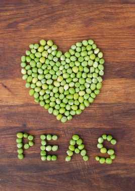 Taze yerel olarak yetiştirilen yeşil bezelye ahşap arka plan üzerinde yapılan kalp