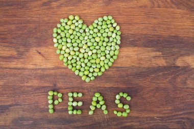 Taze yerel olarak yetiştirilen yeşil bezelye ahşap arka plan üzerinde yapılan kalp