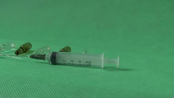 Медицинские шприцы и флаконы на зеленом фоне — стоковое видео
