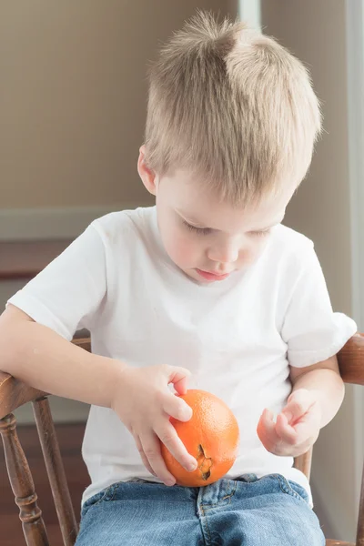 Niño pelando naranja —  Fotos de Stock
