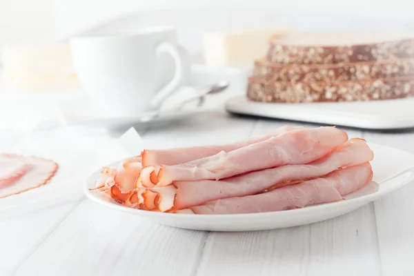 Sliced ham rolled up on white plate — Stock Photo, Image