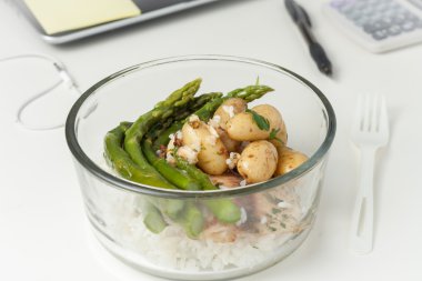 a glass container with lunch on a desk at work clipart