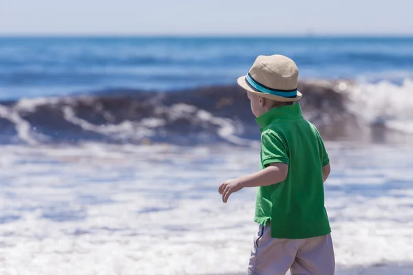 Kleine jongen op zoek naar grote oceaan golven — Stockfoto