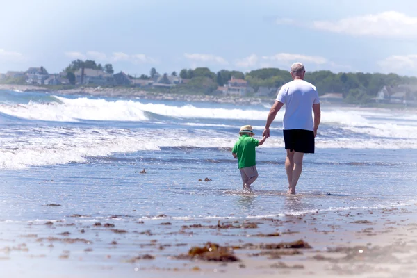 Abuelo con su nieto caminando en una playa — Foto de Stock