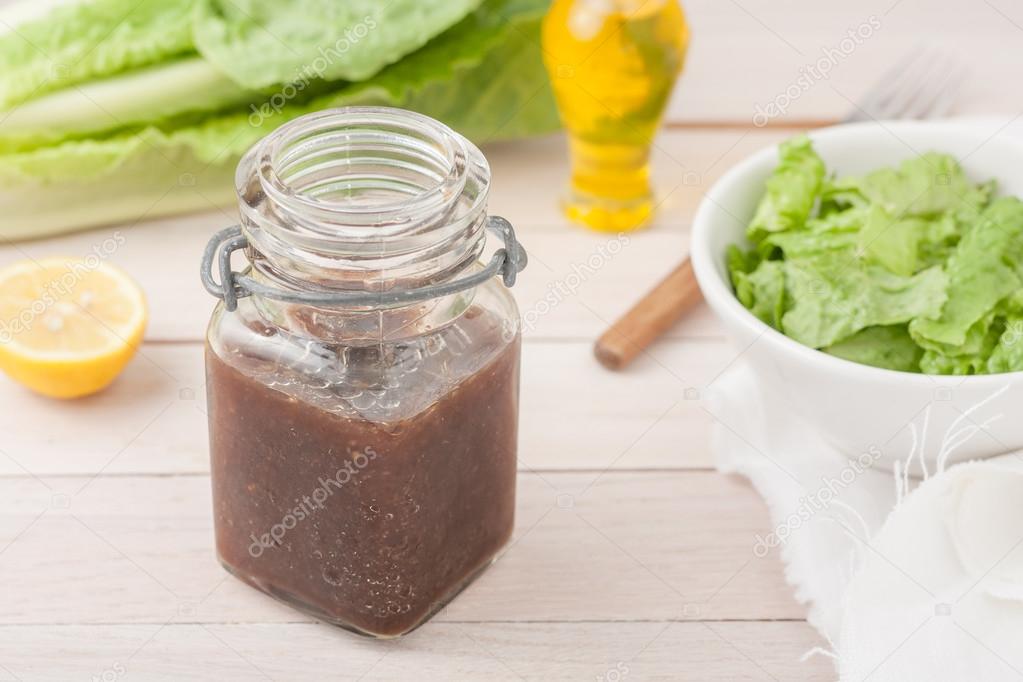 balsamic vineaigrette salad dressing in a glass container on light wooden background