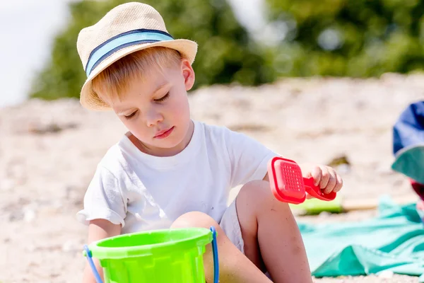 Peuter jongen spelen met zand sifter op een strand — Stockfoto