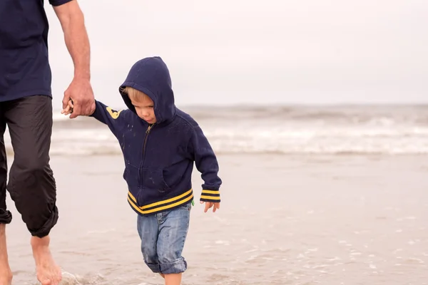 Adorable obediente niño caminando en una playa cogido de la mano con su padre — Foto de Stock