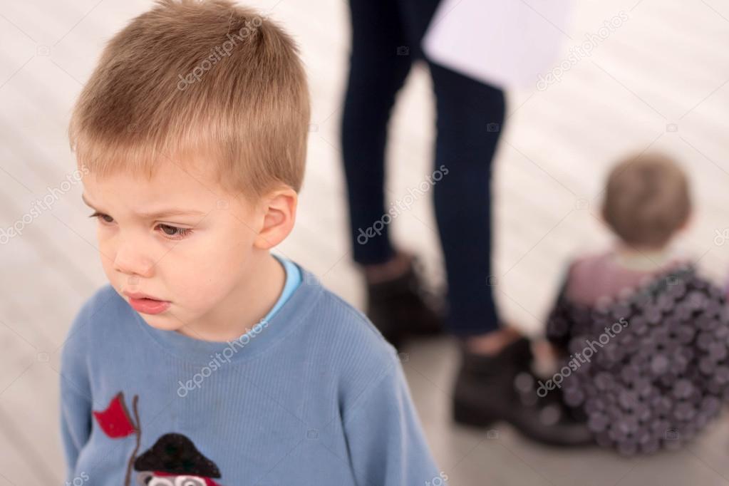 sad boy jealous about being neglected by his mother or caregiver who is giving attention to another child