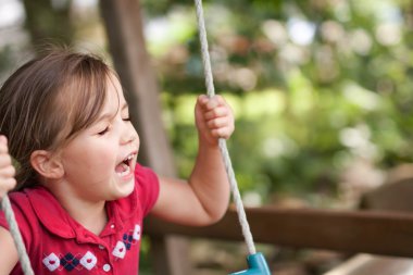 Korkudan çığlık bir salıncak üzerinde küçük bir kız korkuyor