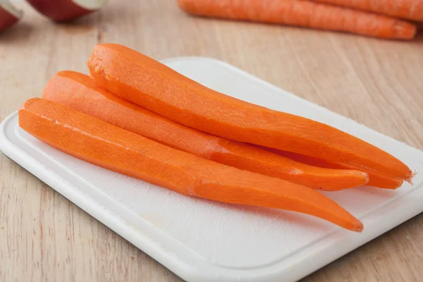 Fresh peeled long carrots on white chopping board — Stock Photo, Image