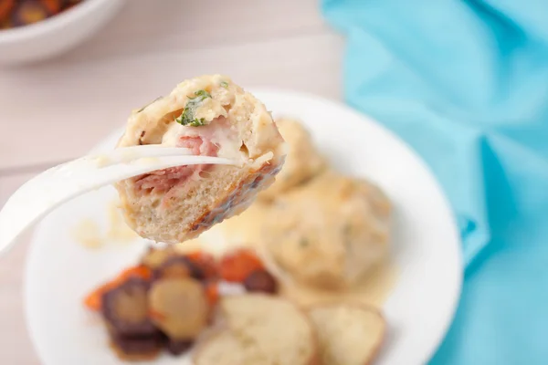Un tenedor con un trozo de albóndiga hecho con carne blanca molida, jamón, queso y perejil servido con verduras asadas y salsa de vino blanco — Foto de Stock