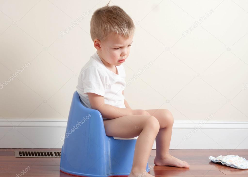 sad toddler boy wearing a white t-shirt sitting on a potty